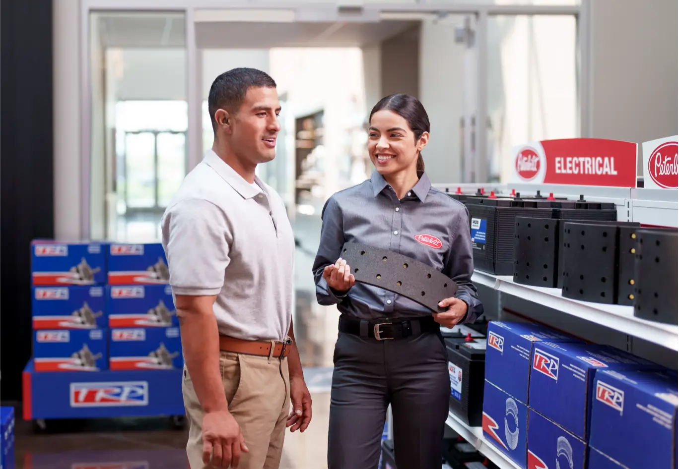 A Peterbilt clerk explains a part to a customer in a dealership